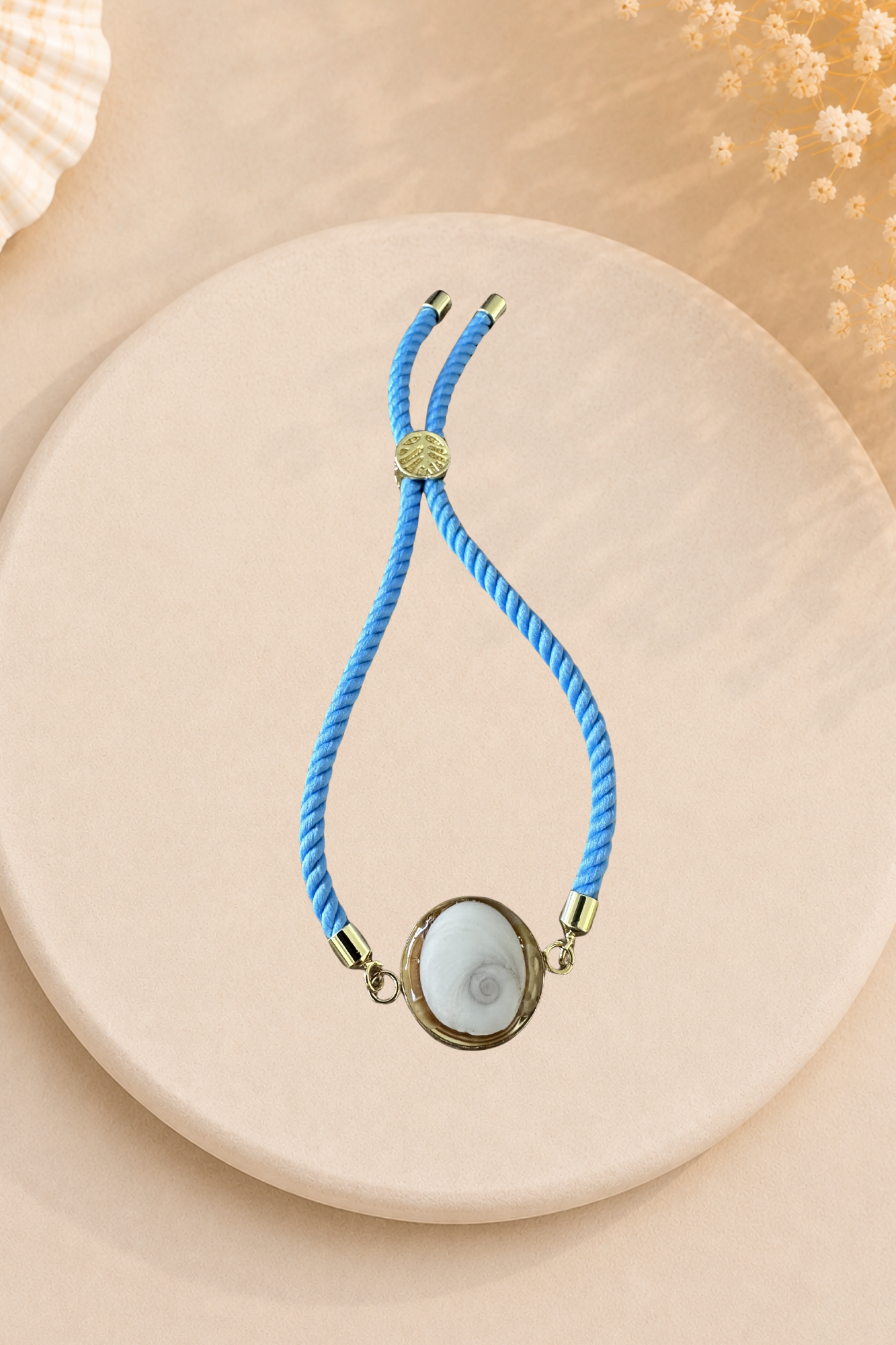 Bracelet femme Œil de Sainte‑Lucie sur cordon bleu pale et médaillon doré. Bijou artisanal, chic et porte‑bonheur méditerranéen, élégant au quotidien.