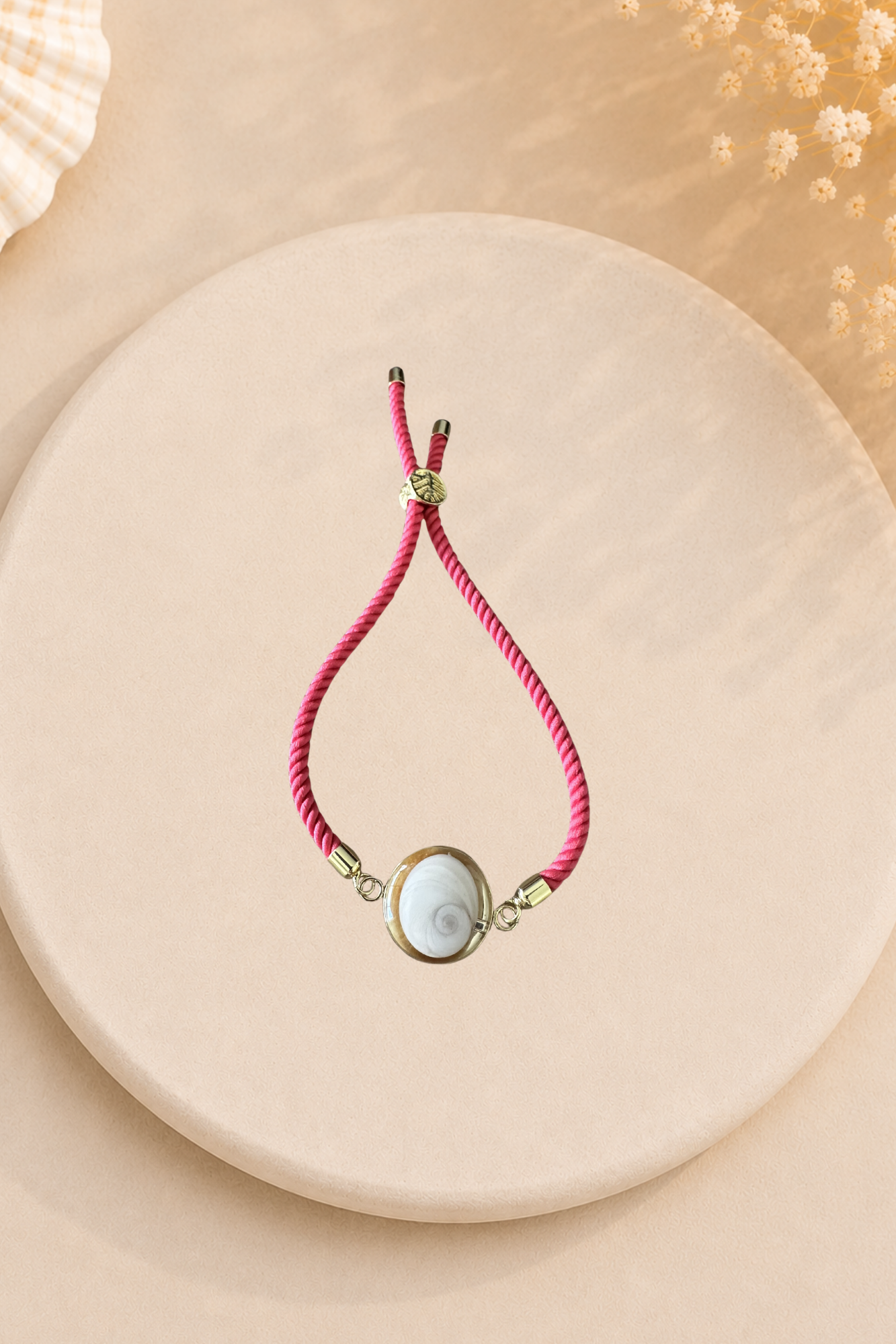 Bracelet femme Œil de Sainte‑Lucie sur cordon framboise et médaillon doré. Bijou artisanal, chic et porte‑bonheur méditerranéen, élégant au quotidien.