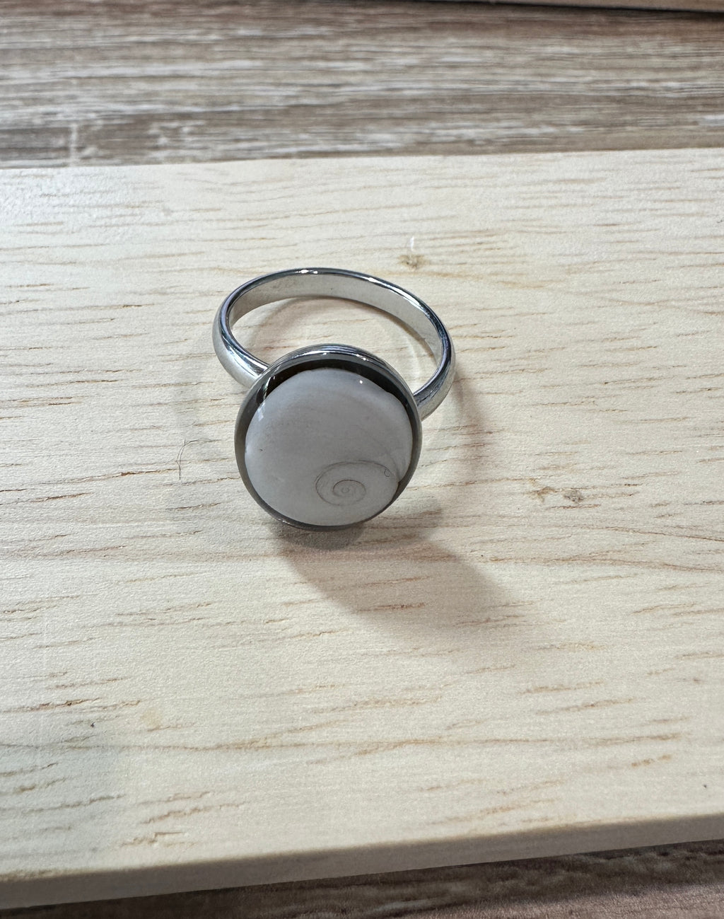 Bague Iris argentée, vue de trois-quarts sur fond bois