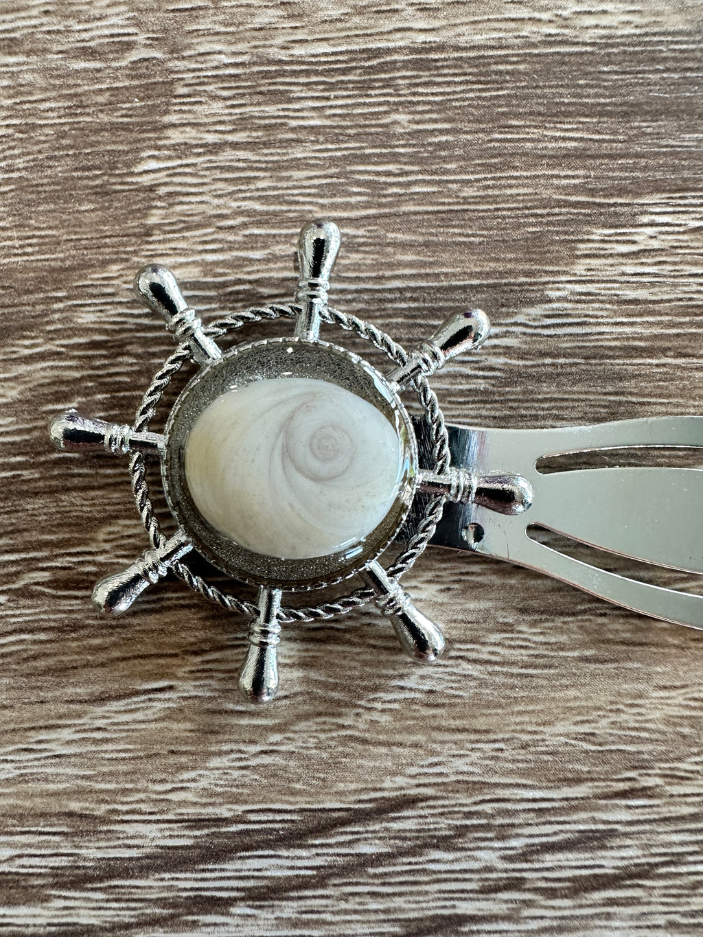 Gros plan sur le marque-page argenté en forme de gouvernail avec cabochon Œil de Sainte-Lucie