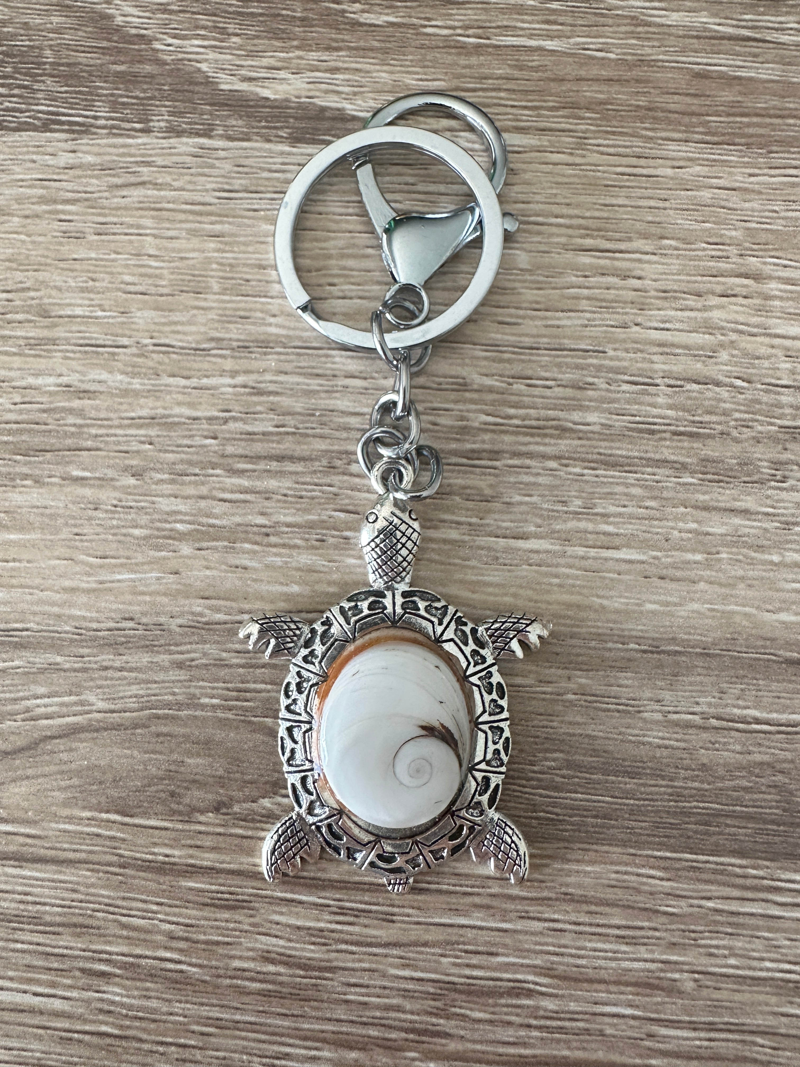 Porte-clés tortue argenté avec cabochon Œil de Sainte-Lucie clair, posé à plat